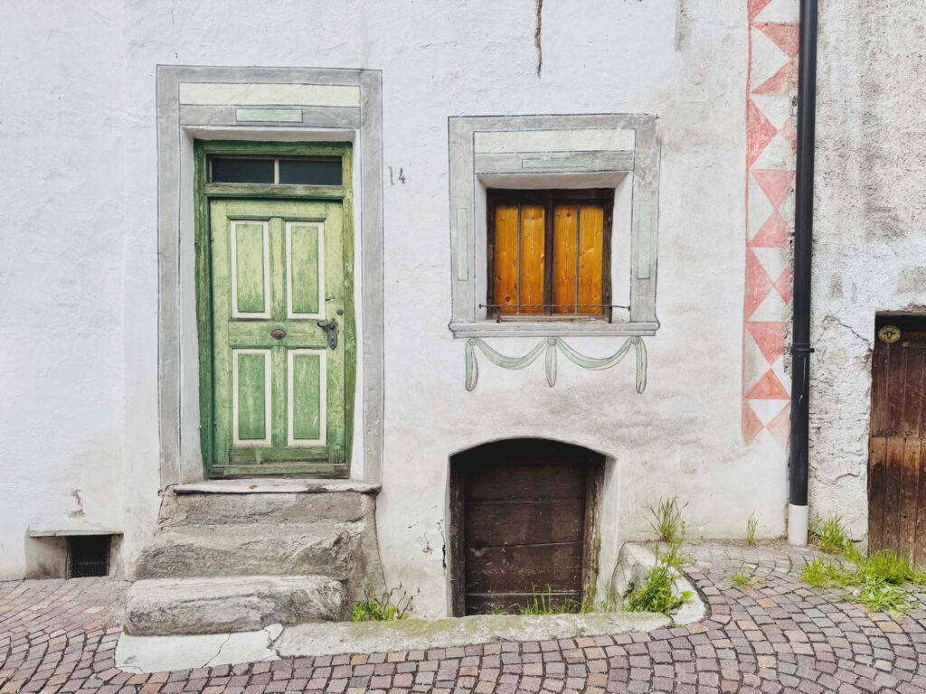 Sehr altes Haus mit grüner Holztür über eine schmale Steintreppe erreichbar mit kleinem Fenster und Zugang zum Keller
