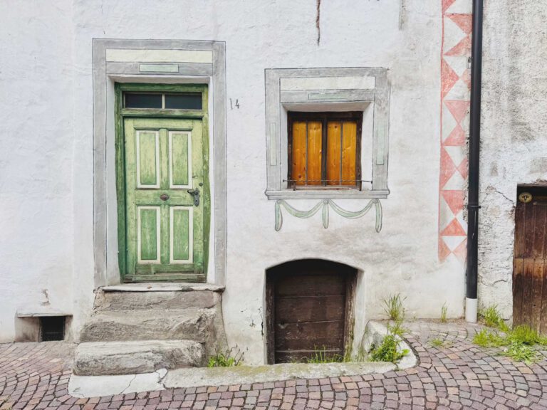 Sehr altes Haus mit grüner Holztür über eine schmale Steintreppe erreichbar mit kleinem Fenster und Zugang zum Keller