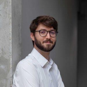 Porträt von Tim Tornow, mit Brille, weißem Hemd und Bart